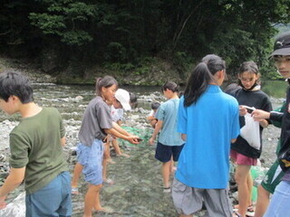 写真：子どもたちが川でマスのつかみ取り体験をしている様子