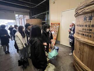 写真：しょうゆ蔵の工場見学で説明を聞いている様子