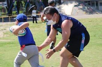 写真：選手と子供が一緒にタグを取り合っている様子