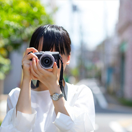 写真：カメラで写真を撮る女性