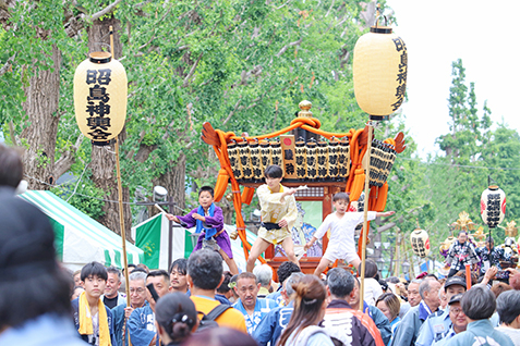 おみこしの上で指揮をとる3人の写真