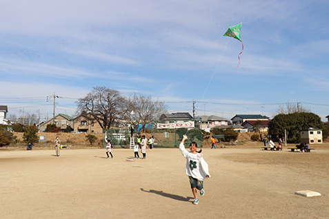 走りながら凧を上げる子どもの写真