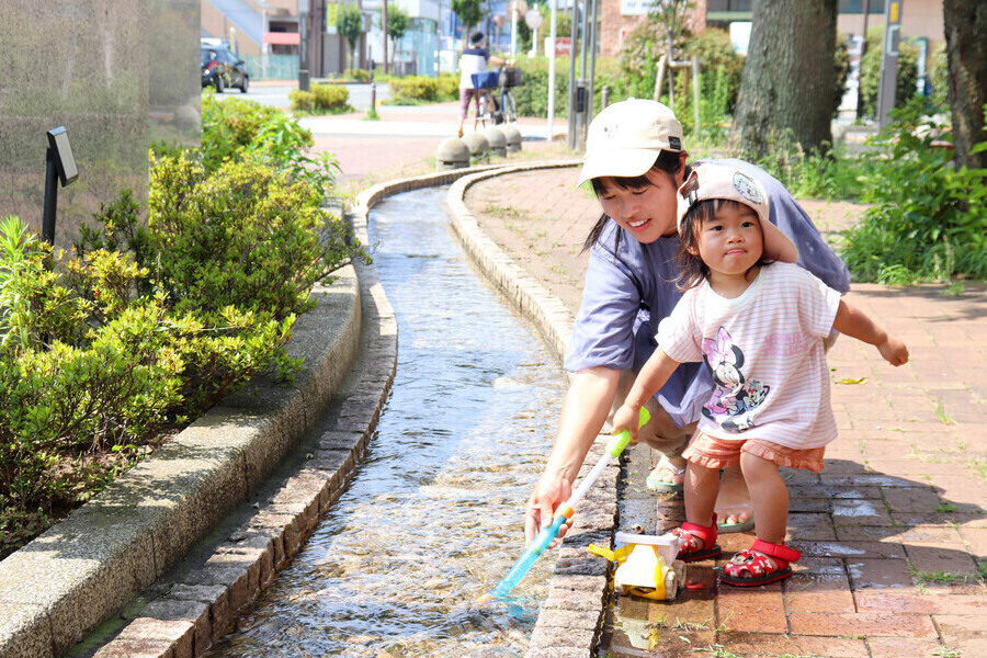 写真：せせらぎで遊ぶ親子