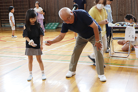 子どもと高齢者がコマを回している写真