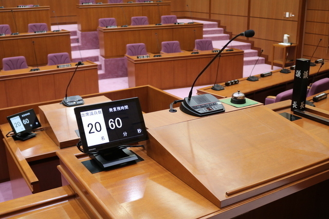 小型モニターが設置された演壇と議長席の写真